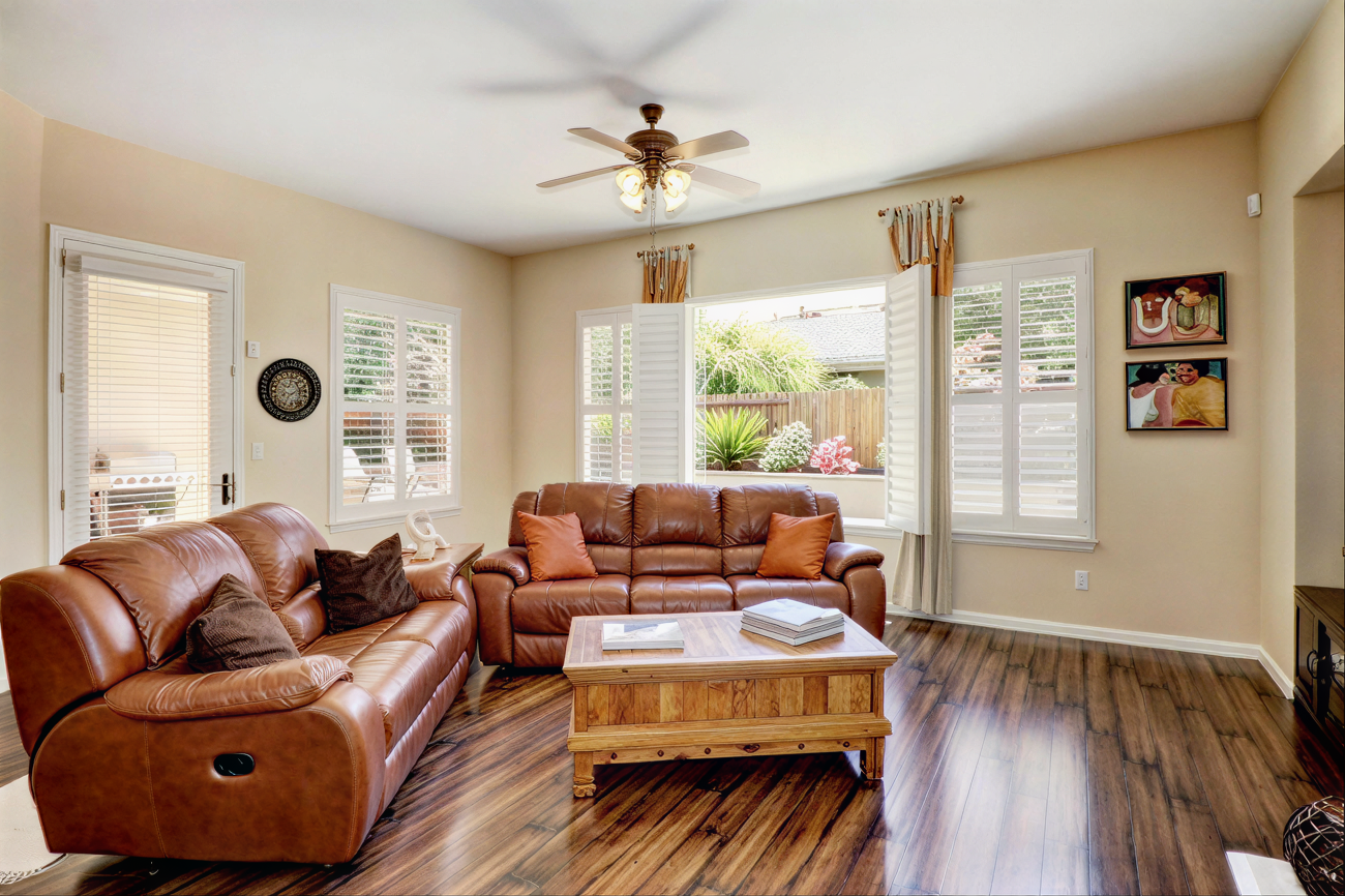 Living room with leather couches and ceiling fan